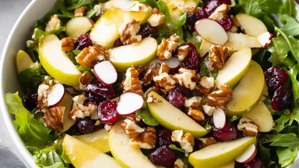 an apple cranberry walnut salad is being poured into a bowl