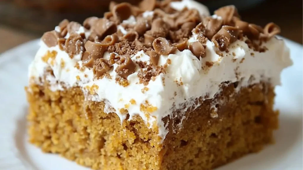 pumpkin spice poke cake in a glass pan with caramel sauce being poured on top