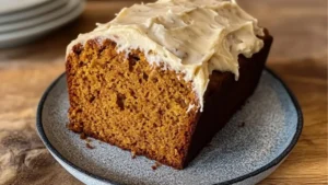 pumpkin loaf topped with cream cheese icing on a cutting board and text overlay that reads, pumpkin loaf topped with cream cheese icing
