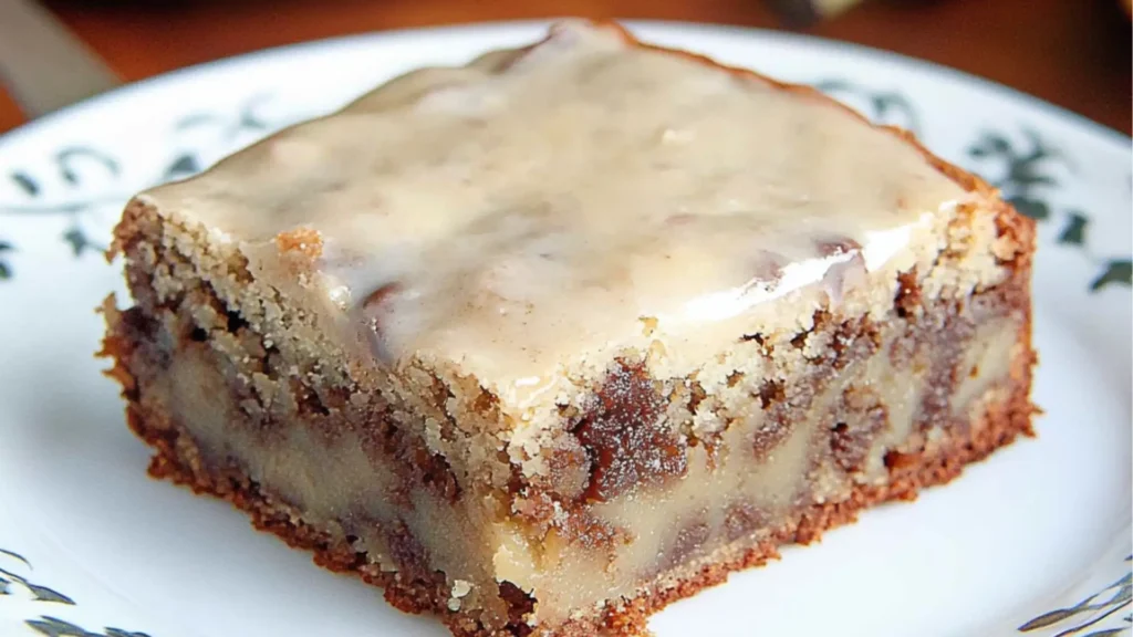 banana bread brownies with vanilla frosting on a white and blue plate next to a fork