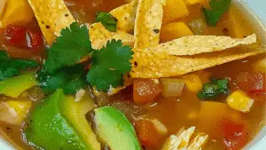 chicken tortilla soup with tortilla chips and avocado on the side