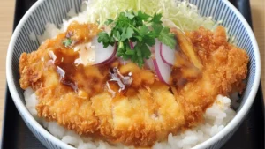 a bowl filled with rice and meat covered in sauces next to chopsticks