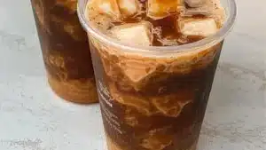 pumpkin spice cold brew with cinnamon and whipped cream in glasses on a white tablecloth