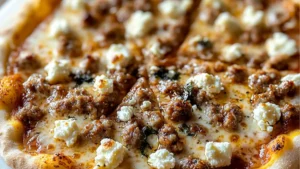 a slice of pizza with meat and cheese on it sitting on top of wax paper