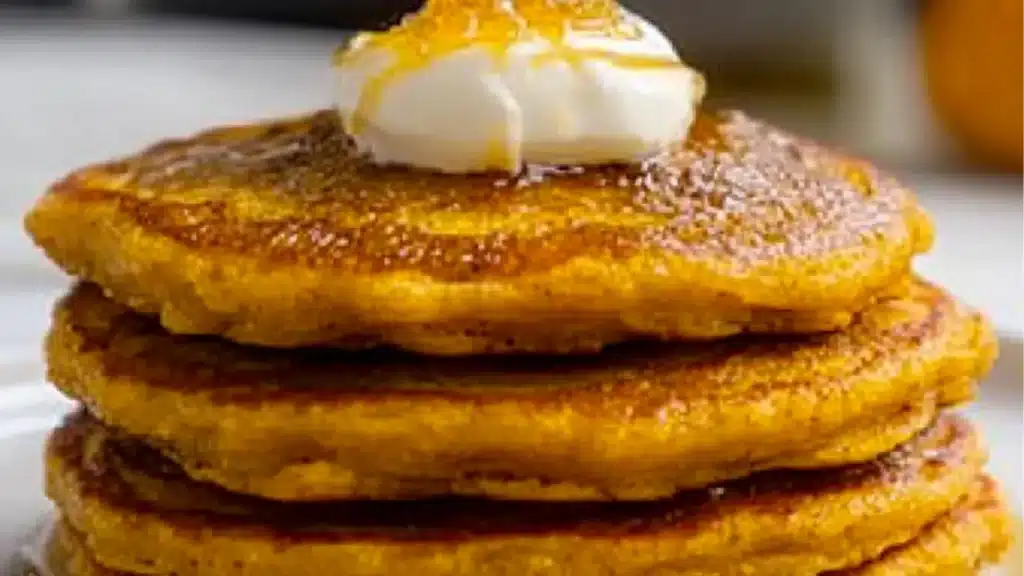 pumpkin greek yogurt pancakes on a plate with syrup and butter in the middle