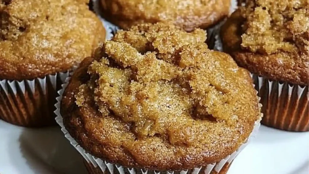 some banana bread muffins are on a cooling rack and one has chocolate chips
