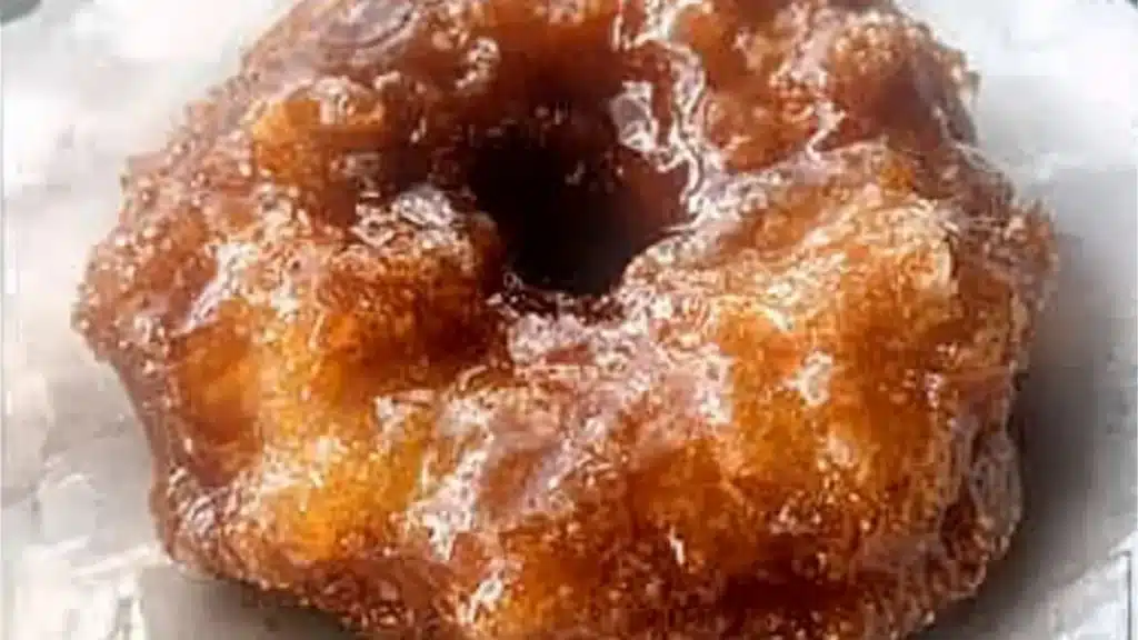 Freshly baked apple fritter donuts with warm spices and sugary glaze on top.
