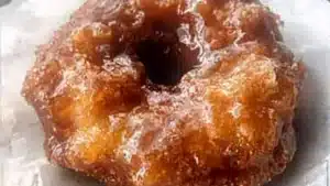 Freshly baked apple fritter donuts with warm spices and sugary glaze on top.