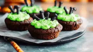 chocolate cupcakes with green frosting and googly eyes on them, topped with candy sticks