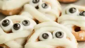 four halloween pretzels with googly eyes and white frosting on them are lined up in a row