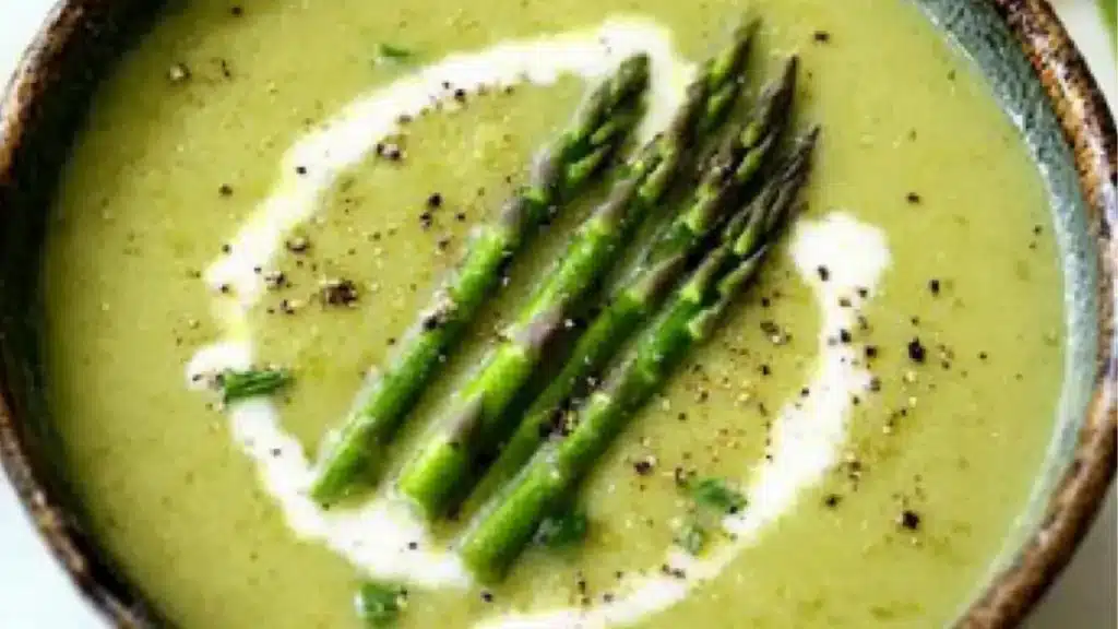 a bowl of soup with a spoon and text overlay that reads simple asparagus soup