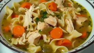 chicken noodle soup with carrots and parsley in a bowl