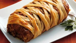 an overhead view of a meatloaf with googly eyes and text overlay that reads, quick & tasty mummy meatloaf best spook comfort food