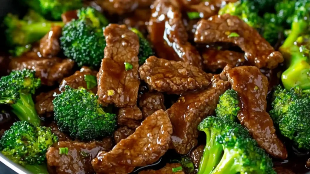 a bowl filled with beef and broccoli on top of a pink table cloth