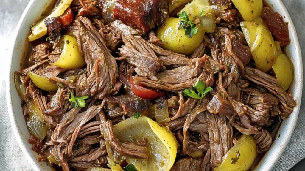 slow cooker italian beef with peppers and onions on a white plate next to the recipe title
