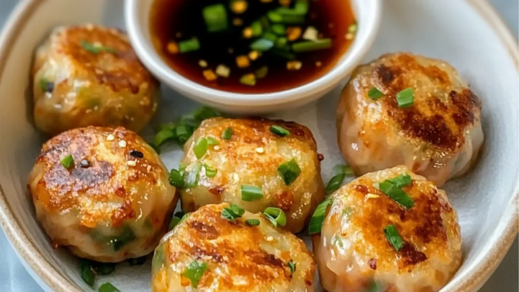 there are pieces of food on the plate with dipping sauce in the bowl behind it