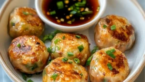 there are pieces of food on the plate with dipping sauce in the bowl behind it