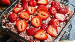 a close up of a piece of cake with strawberries on top and the words gooey strawberry earthwake cake above it