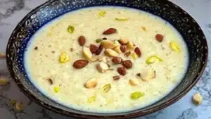 bowl filled with creamy kheer rice and topped with nuts, served on top of