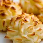 three baked potatoes on wax paper with some green sprigs in the middle and one is yellow