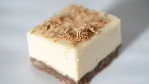 how to make cheesecake fudge on a cutting board with text overlay that reads, how to make cheesecake fudge