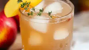 vanilla bourbon cider cocktail with cinnamon sticks and an apple in the background