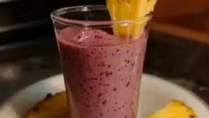 a smoothie with cranberry and pineapple is in a glass on the table