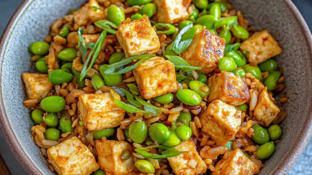 a bowl filled with rice and peas on top of a blue table cloth next to a fork