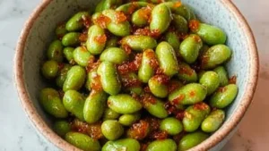 garlic edamame in a bowl with sesame seeds on top and the words easy 30 minute 10 minute garlic edamame