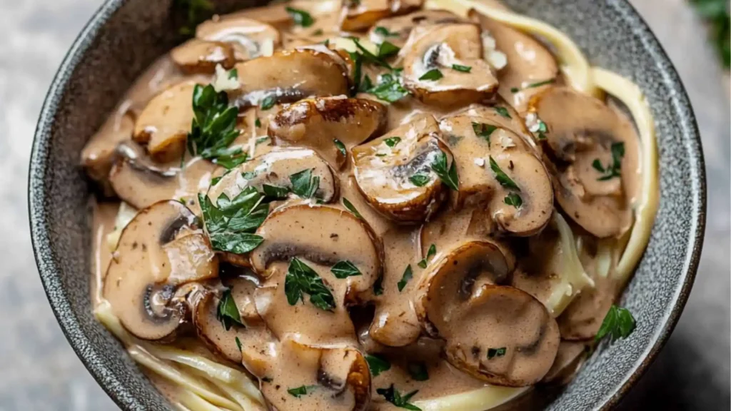 mushroom stroganoni in a red skillet with text overlay that reads, mushrooms stroganonoff