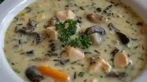 creamy mushroom, chicken and wild rice soup with bread on the side is ready to be eaten