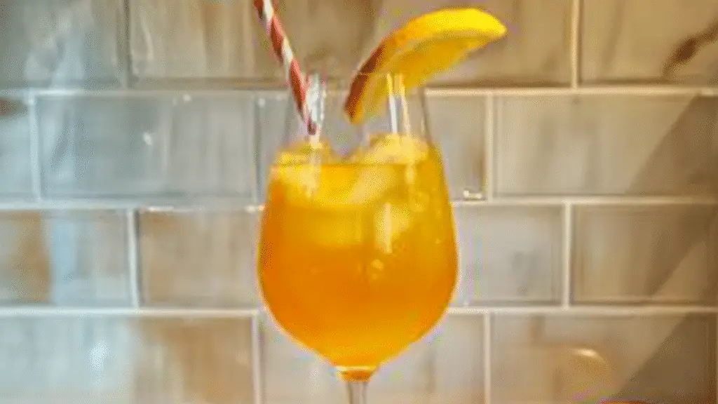 glasse filled with orange juice and topped with cherries on a colorful table cloth