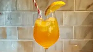 glasse filled with orange juice and topped with cherries on a colorful table cloth