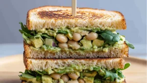 a sandwich with avocado and bread on it that says high protein avocado white bean sandwich