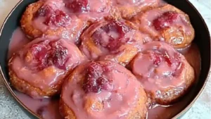 some kind of dessert with pink icing on top and sprinkles all over it