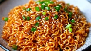 someone holding chopsticks over a bowl of noodles with sesame seeds and scallions