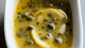 a pan filled with lemon caper sauce on top of a table