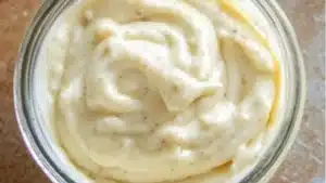 a bowl filled with mayonnaise on top of a wooden table