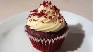 someone is holding a pink cupcake with sprinkles in the shape of a heart
