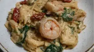 Creamy Tuscan Shrimp Orzo with Spinach, Sun-Dried Tomatoes, and Artichokes - in a cast iron skillet.