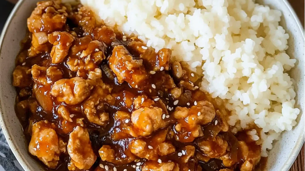 an orange chicken and rice dish with broccoli on the side, in a white bowl