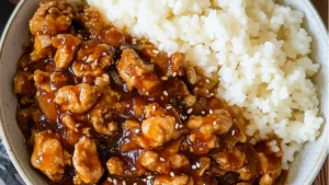an orange chicken and rice dish with broccoli on the side, in a white bowl